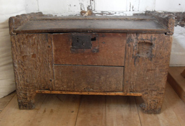 For a large number of people among the middling sort in early modern England, a commitment to Christianity went hand in hand with folkloric belief. This late medieval coffer or ark (a type of chest) was originally used to store grain. Raised from the floor by its feet, it protected precious goods from the dirty and often damp ground. The lock seen on the front provided further security against thieves. Foodstuffs such as grain and malt were necessary provisions for making bread and beer.  They were also valuable to members of the middling sort as they could be traded.<br />
<br />
A households sustenance and livelihood might depend on these goods, so they had to be kept safe from all threats, including those offered by supernatural beings. Circular marks were inscribed into the lid of this otherwise plain item. This graffiti is believed to date from the early 1600s and is similar to marks found on wooden objects (like bowls) and on timber beams in buildings. These ritual marks, usually symbolising God (circles symbolising eternity) or the Virgin Mary, were intended to ward off spirits such as fairies or the familiar creatures used by witches. Their appearance on this grain ark suggests that the owner was particularly worried about maleficent forces corrupting the goods inside.  