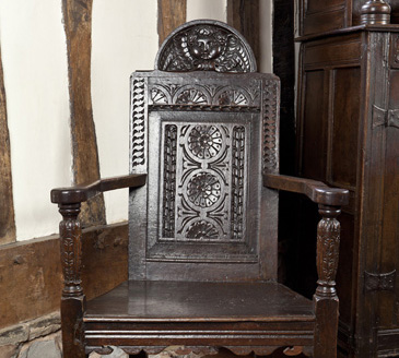 A wooden armchair was an exclusive item for the master (sometimes mistress) of the household. Such items were made by specialist craftsmen called joinersbecause of the method of making framed structures held together with joints. Joined items were more costly and desirable than basic furniture and could be enriched further with turned supports and finials (another specialist skill in carpentry, turned on a lathe) and carved decoration.<br />
<br />
This chair combines all these features. Middling houses had very few chairs; most people sat on stools or benches. Armchairs symbolised status and authority not only in the domestic context but also in administrative bodies such as town corporations, guilds and church vestry meetings. This example, made by a successful workshop in Salisbury, is a very high-quality item with its level of decoration showing expert craftsmanship. This kind of object would have stood out to all visitors as strikingly new and fashionable.