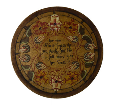 This small wooden plate was known as a trencher and is part of a set of twelve. Each trencher is an elaborately painted roundel: a small, decorated disc. Fruits and flowers are painted on one side of this trencher, along with a short inscription. The text is a proverb, a warning or comment on daily life and morality.<br />
<br />
Sets of trenchers such as this were often used to serve sweet treats as an additional banquet course after dinner. The trencher would be placed onto the table with the painted side down, and marzipan or other sugary delights would then be served on the plain surface. Guests could flip their trenchers having eaten their sugary confection and only then would the delicate decoration and moralising text be revealed. Guests might even be encouraged to read their text aloud to the table as a form of after-dinner entertainment.<br />
<br />
These trenchers demonstrate the two sides of leisure for middling people: socialising and entertainment, but with due respect to propriety and morality. Objects such as the posy trencher show how these aspects of middling life could be brought together during leisure time.