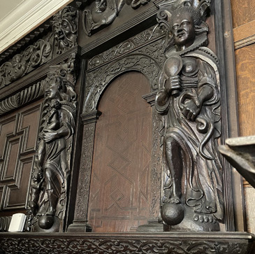 This grand carved wooden overmantel was salvaged in the early years of the 20th century from 32, Carr Street in Ipswich and is now on display in the Christchurch Mansion Museum. It has four large figures representing the virtues of Faith, Hope and Charity (the three theological virtues) along with Prudence, one of the four Cardinal Virtues (with Justice, Fortitude and Temperance). These female personifications are identified through the objects that they hold (their attributes). The ability to read these objects and correctly identify the nature of these allegorical figures was an essential part of the visual literacy of sixteenth and seventeenth century England. The Virtues were an ancient iconography that would have been familiar in late medieval church art. They continued to be depicted across the visual arts of early modern England, in tapestry and painted cloth, in print and in interior decoration.<br />
<br />
Here, viewers would know that the cross is the attribute of faith, the anchor represents Hope and that Charity nurses an infant. The mirror and snake held by Prudence, meanwhile, may be surprising to a modern audience given their association with vanity, and sin/the devil. In early modern understanding, however, the snake could symbolise wisdom and the mirror shows self-knowledge; taken together and in the context of the other Virtues the meaning of these symbols is clear. The Virtues were commonly depicted in large-scale domestic decoration where they represented the character and qualities of the upper middling householder; they would have been readily understood as such by all visitors to the house regardless of their ability to read or write.  