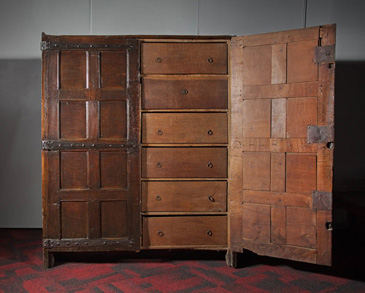 The Stratford-upon-Avon town Corporation had this cupboard of boxes (drawers) made in 1594 for the storage and organisation of their records. The cupboard was kept on the first floor of the Guildhall, alongside other storage items. It facilitated the reference and retrieval of information by town officials. In this way, the cupboard acted as a memory aid for the towns corporation, allowing documents to be stored in logical order. Muniments (legal documents) stored and created within a town were important to the establishment of authority.<br />
<br />
Good governance depended upon a towns ability to record, organise and retrieve legal documents as required. As a result, new kinds of storage furniture, such as this cupboard with drawers, worked alongside records written by educated administrators whose responsibility it was to maintain the reputation of their local community. For men involved in civic governance, writing was an important tool through which they could craft a perception of their town, have legal and political influence, and create a legacy through documentary evidence. 