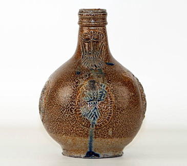 These were the plastic bottles of their day, turning up very frequently now in archaeological digs (including at the Curtain playhouse, e.g.) and on mudlarking expeditions. Middling men and women would own, encounter, inherit, and purchase jugs decorated with faces like these. These so-called Bartmann or Bellarmine jugs originated in the Rhineland in Germany, from whence they were used to transport liquids across the sea in ships (they also show up frequently in shipwrecks). Characterised by their bearded face and distinctive shape, once they arrived in England, they were used to store foodstuffs, wine, or other liquids. This kind of vessel would therefore have been a familiar sight to almost every individual in the country, although the middling sort are likely have owned them in larger numbers than their less wealthy peers, because they were able to produce and store liquids in larger quantities for future consumption. Such items were broadly known in England as Cologne ware, indicating a connection between this everyday object and their (vague) location on the continent. <br />
<br />
Throughout the 1500s and 1600s, German stonewares furnished English households and inns with jugs, pots, jars, and other itemsdirect from the source or through copy-cat workshops. The daily experience of our middling sort, particularly surrounding food and drink, is therefore deeply ingrained with European manufacture and design. <br />
<br />
The iconographic significance of the bearded wild-man face on this jug emphasises northern European folk roots. One of the names by which these jugs are now known, Bellarmine, refers to the French inquisitor Robert Bellarmine, who persecuted protestants, and they therefore also carry with them a religious significance that imbues the everyday uses of these vessels with religious iconography.  