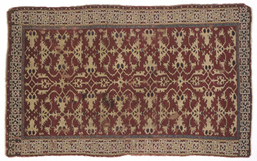 This brightly patterned carpet is the type of soft furnishing we might expect to find in an upper-middling home at the end of the 1500s and the start of the 1600s. In this period, carpets were used to cover tables and cupboards rather than floors (which were spread with rushes). This carpet is from Turkey and features a popular lotto design. <a href='https://collections.vam.ac.uk/item/O11051/carpet-unknown/' target='_blank'>V&A</a> research suggests that such objects were woven in commercial workshops in Western Turkey and then exported to central and western Europe in the 1500s and 1600s. The two main trade routes into Europe were along the rivers Rhine and Danube, or across the Mediterranean Sea. These were ancient trade routes, and it was not unusual for Turkish goods to find their way to English shores in the 1500s. <br />
<br />
Turkish textiles were used to make a variety of soft furnishings, from carpets to cushions and other chair coverings. Often recorded as turkey or turkey work, wills and inventories show that these textiles reached middling as well as elite homes. Around 25% of provincial urban inventories listed a carpet, for example, suggesting that they were key items of aspirational middling status, owned by those who wanted to signal their social mobility: owning a carpet like this one not only showed your wealth and taste, but also your knowledge of other cultures. In Bristol, for example, John Butcher died in possession of a turkey carpet valued at 25 in 1623.